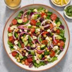 Mediterranean salad in a bowl with Greek dressing alongside.