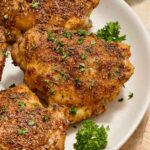 Air fryer chicken thighs on a plate with parsley.