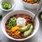 Bowl of ground chicken chili with a spoon digging in.