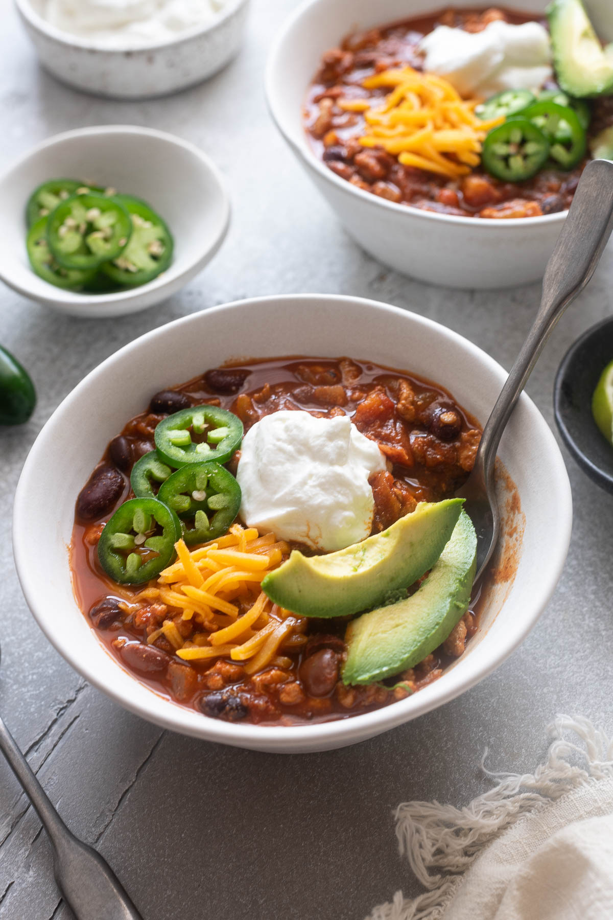 Bowl of ground chicken chili with a spoon digging in.