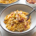 Pumpkin risotto in a bowl with fork digging in.
