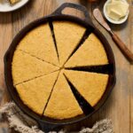 Cornbread in cast iron skillet cut into wedges.