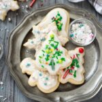 Christmas sugar cookies on a plate with sprinkles.