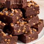 Squares of dark chocolate fudge piled on a plate.