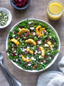 Delicata squash salad in a bowl with dressing alongside.