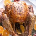 Dry brine turkey on a platter with orange and rosemary.
