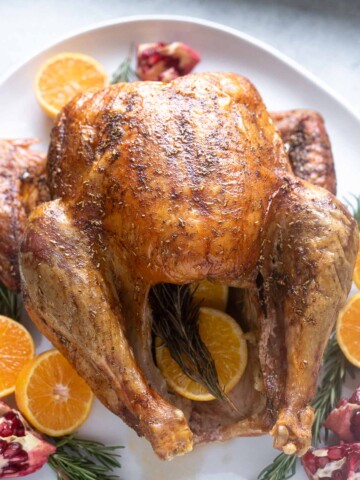 Dry brine turkey on a platter with orange and rosemary.