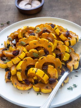 Maple roasted delicata squash on a plate with thyme leaves.