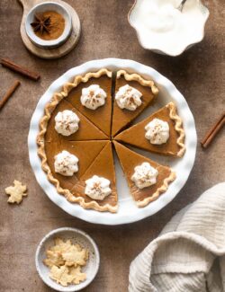 Maple Chai Pumpkin Pie cut in slices and topped with whipped cream.