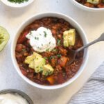 Butternut squash turkey chili in a bowl topped with avocado and sour cream.