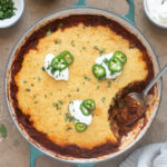 Chili cornbread casserole in pan with spoon digging in.