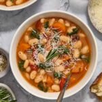 Bowl of vegetarian white bean stew topped with rosemary and parmesan.