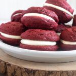 Red velvet whoopie pies piled on a plate.