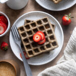 Buckwheat waffles on a plate with strawberry slices.