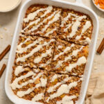 Carrot Cake Baked Oatmeal topped with cream cheese glaze in baking dish.