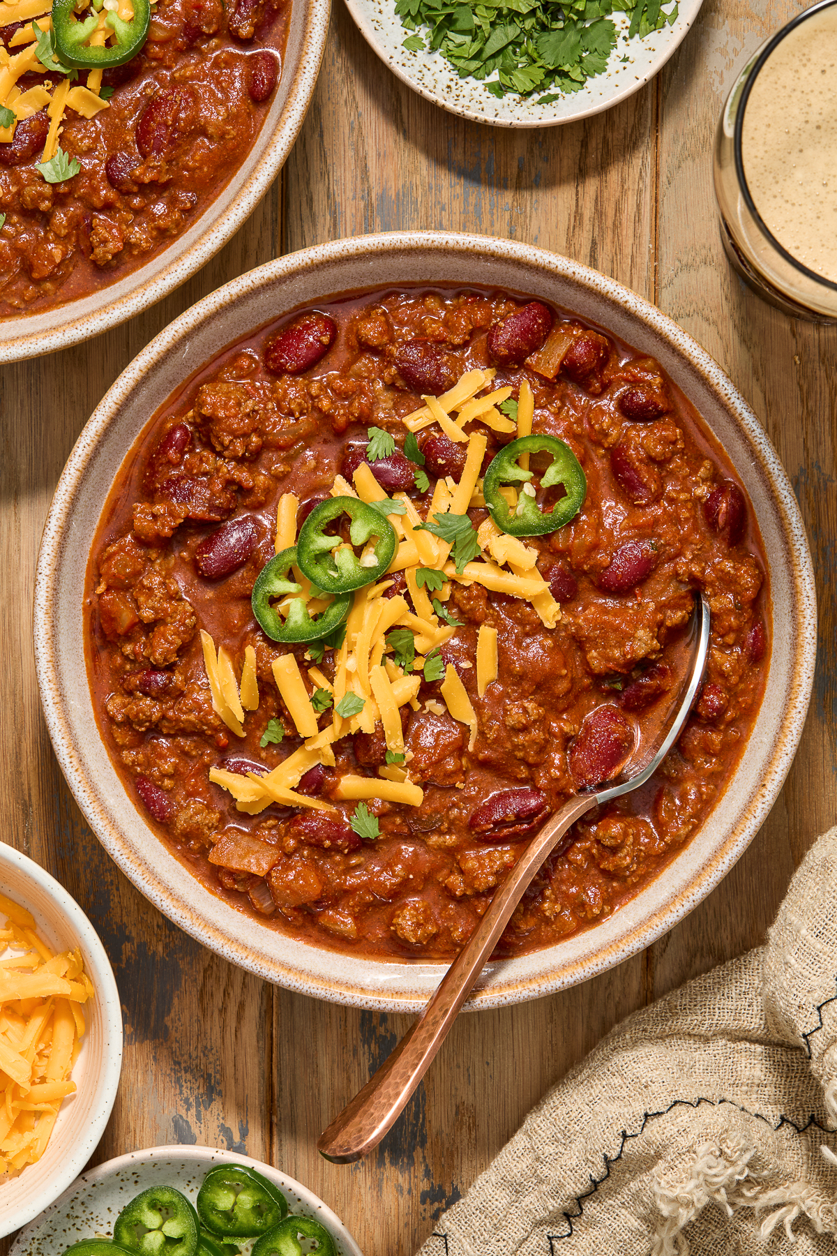 Guinness chili with ground beef in a bowl with cheese and jalapeno slices.