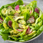 Butter lettuce salad in a bowl with avocado and radish.