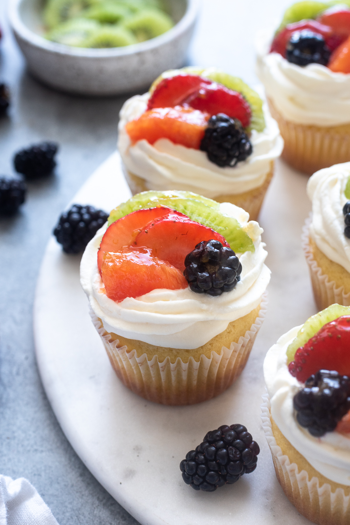 Fruit tart vanilla cupcakes on a serving board.