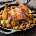 Spatchcock roasted chicken and vegetables in cast iron skillet.