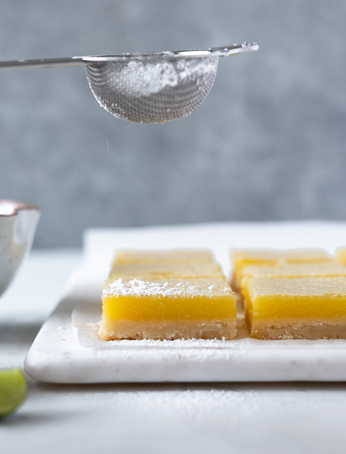 Dust cooled key lime shortbread bars with powdered sugar.