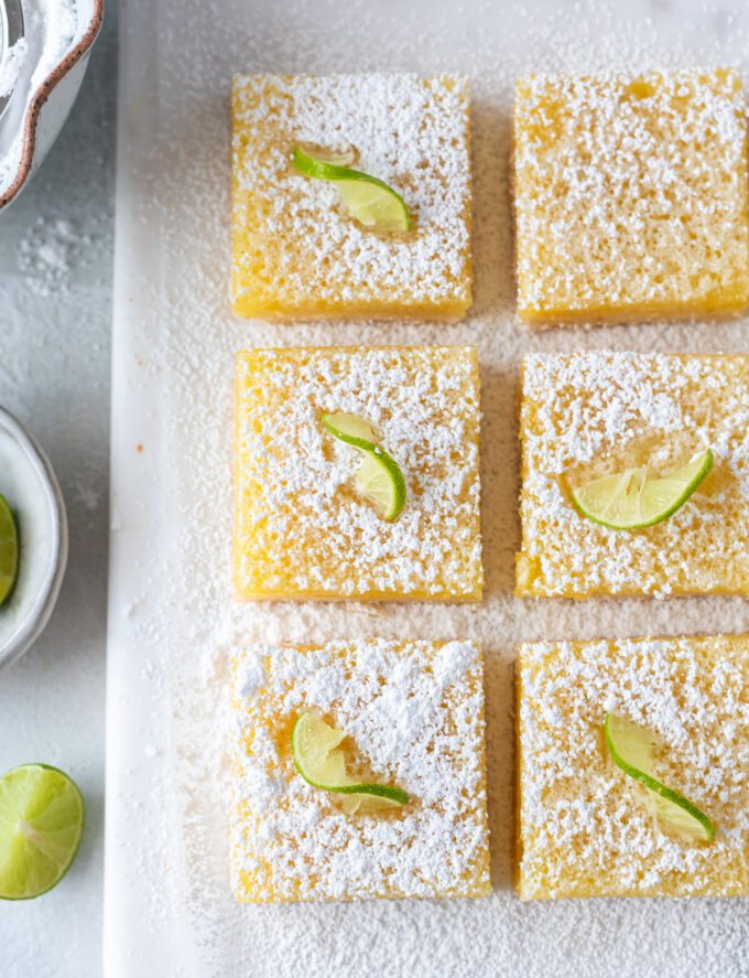 Key lime bars cut into squares with powdered sugar.