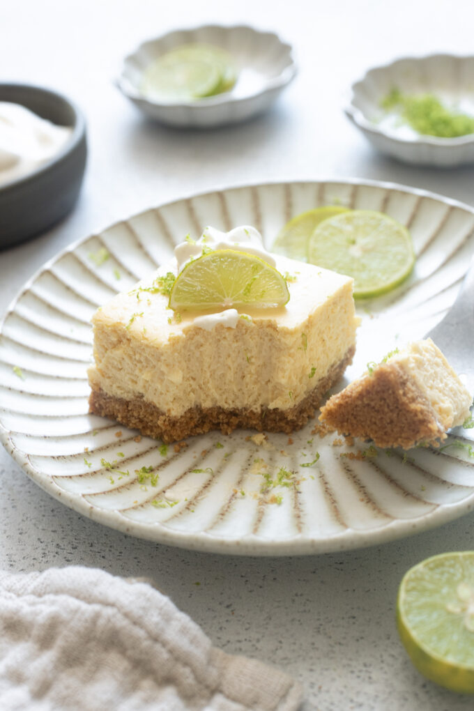 Key lime cheesecake bar on a plate with bite out of it.