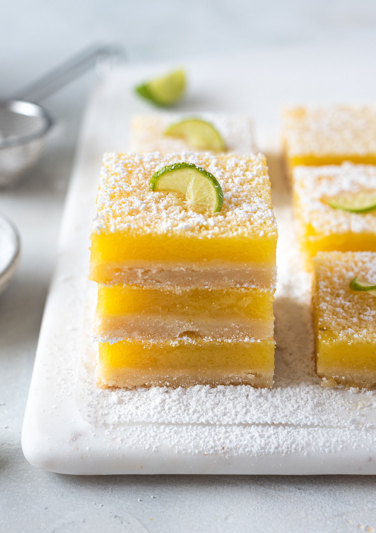 Key lime shortbread bars stacked on top of each other.