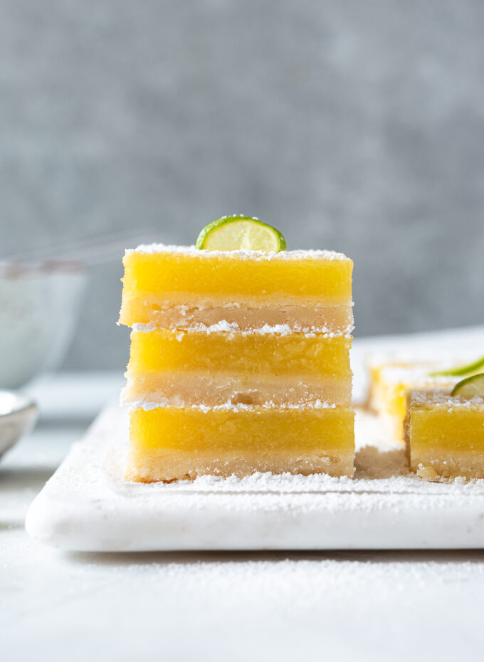 Stack of key lime shortbread bars with lime slice on top.