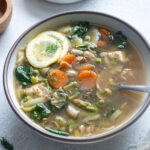 Spring vegetable soup in a bowl with lime slices on top.