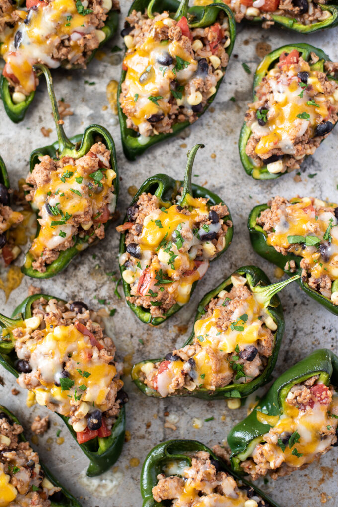 Stuffed poblano peppers with melted cheese on baking sheet.