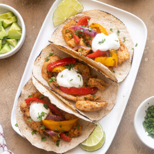 Air fryer chicken fajitas on a platter with toppings.