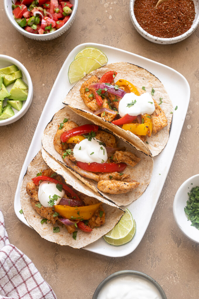 Air fryer chicken fajitas on a platter with toppings.