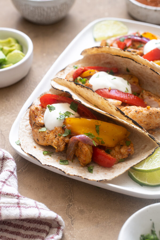 Air fryer fajitas with chicken on a platter with toppings.