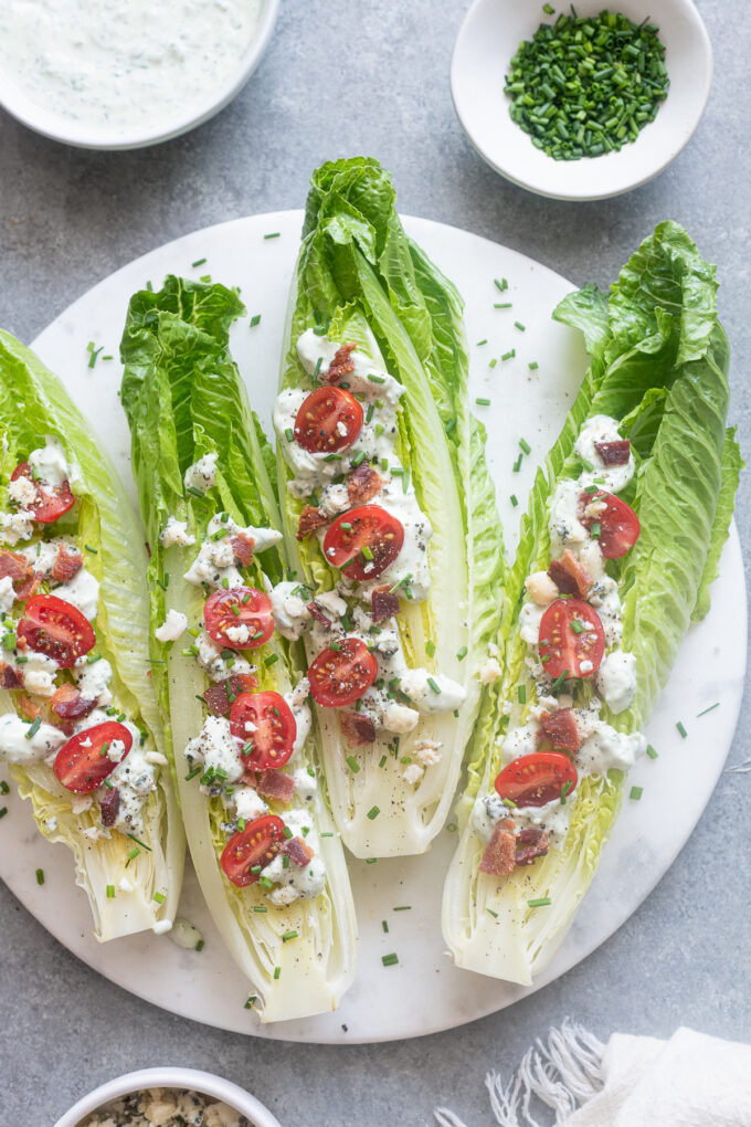 Romaine wedge salads with goddess dressing on a platter.
