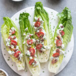 Romaine wedge salad with bacon and blue cheese on a platter.