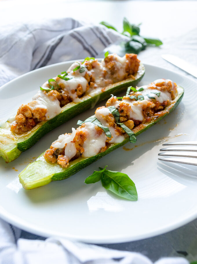 Ground meat stuffed zucchini boats on a plate.
