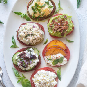 Heirloom tomato flight on a white platter with basil.