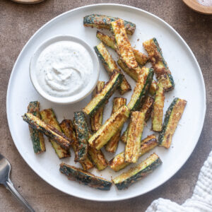 Air fryer zucchini fries on a plate with Greek yogurt ranch dip.
