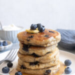 Fluffy Greek yogurt pancakes with blueberries on a plate.
