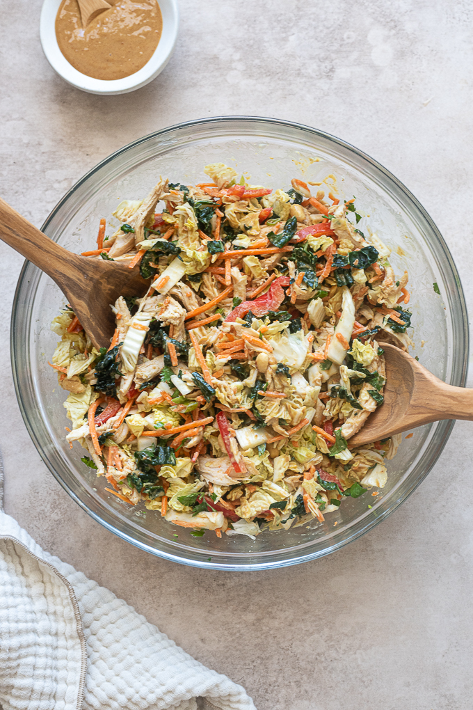 Thai chicken salad with peanut dressing tossed in a mixing bowl.