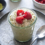 Matcha overnight oats in a jar with raspberries on top.