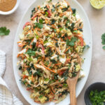 Thai chicken salad on a platter with salad servers.