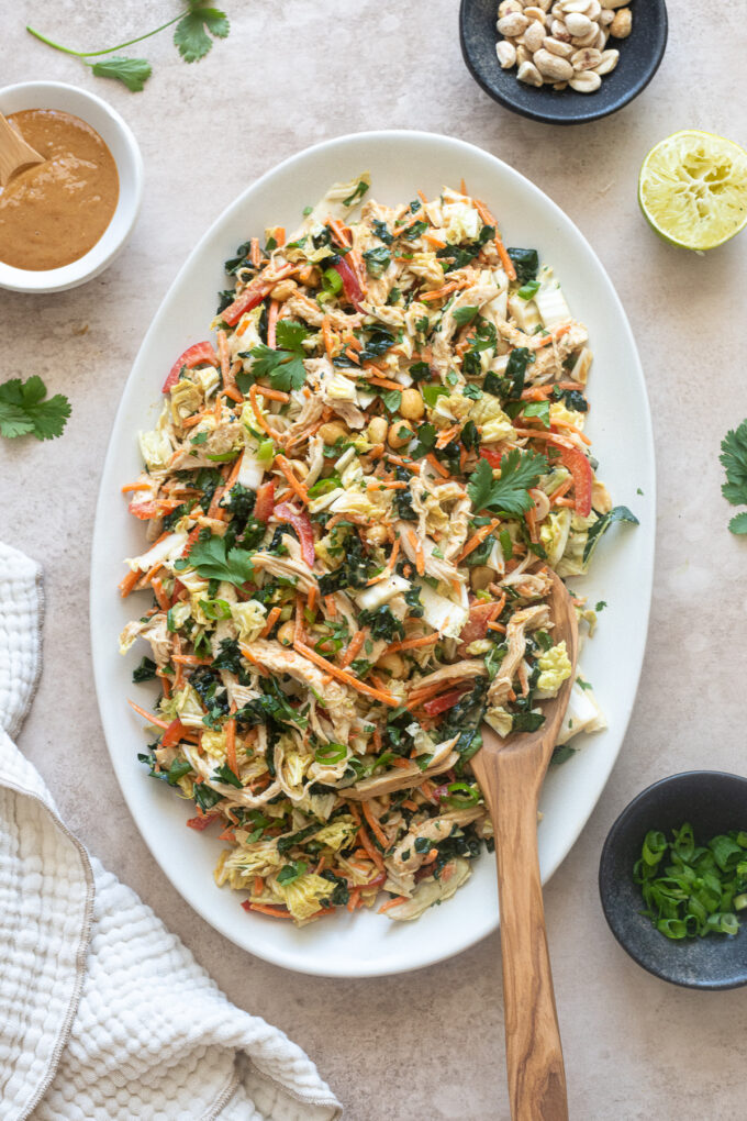 Thai chicken salad on a platter with salad servers.