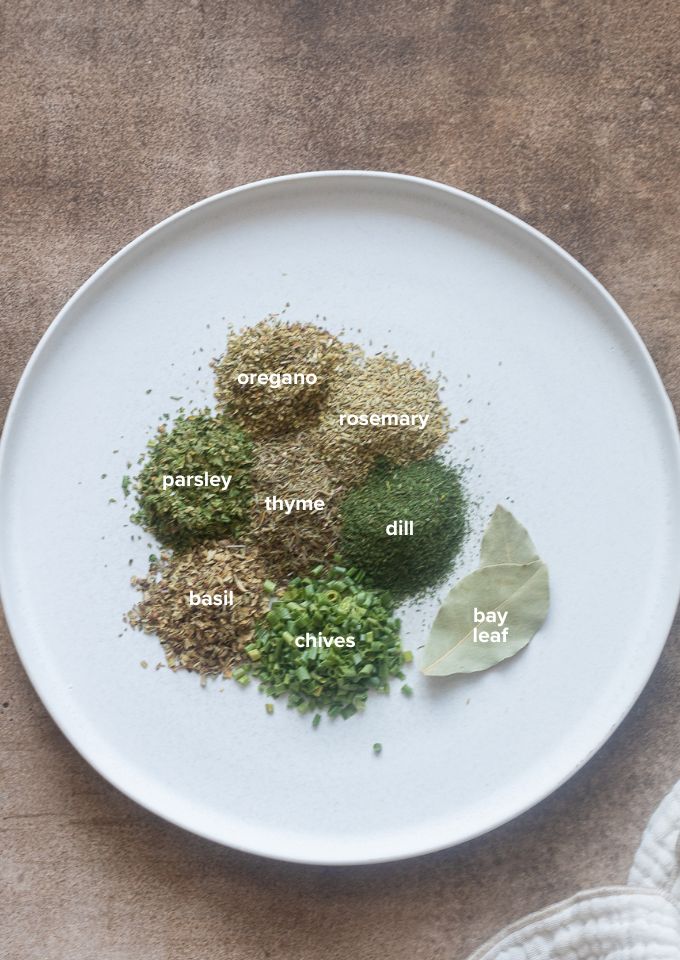 8 commonly used dried herbs labeled on a plate.