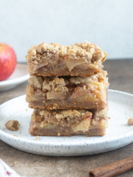 Stack of apple pie bars on a plate.