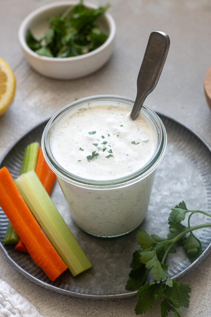 Jar of Greek yogurt ranch dressing in a jar with parsley on top.