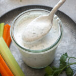 Spoonful of Greek yogurt ranch dressing over a jar.