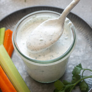 Spoonful of Greek yogurt ranch dressing over a jar.