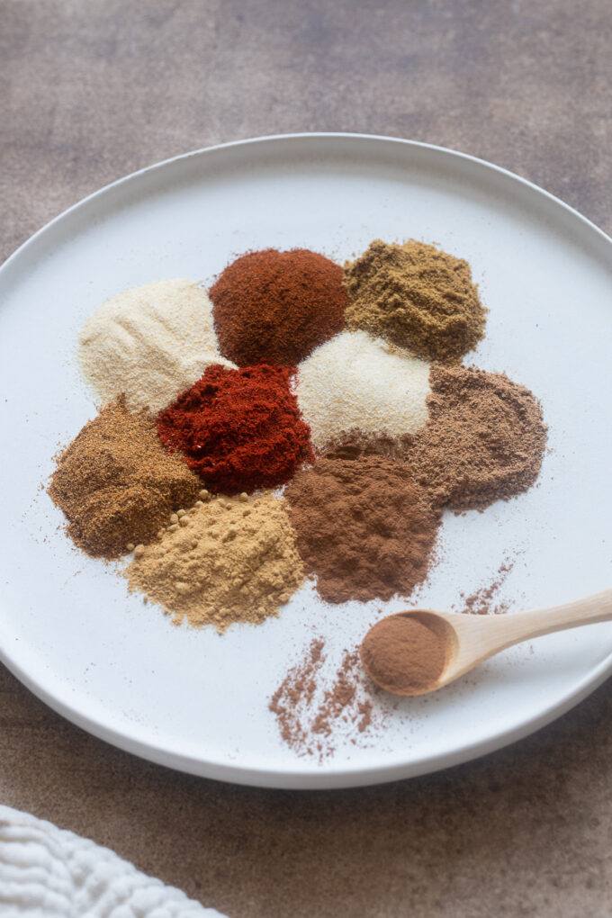 10 Essential spices for spice guide on a white plate.