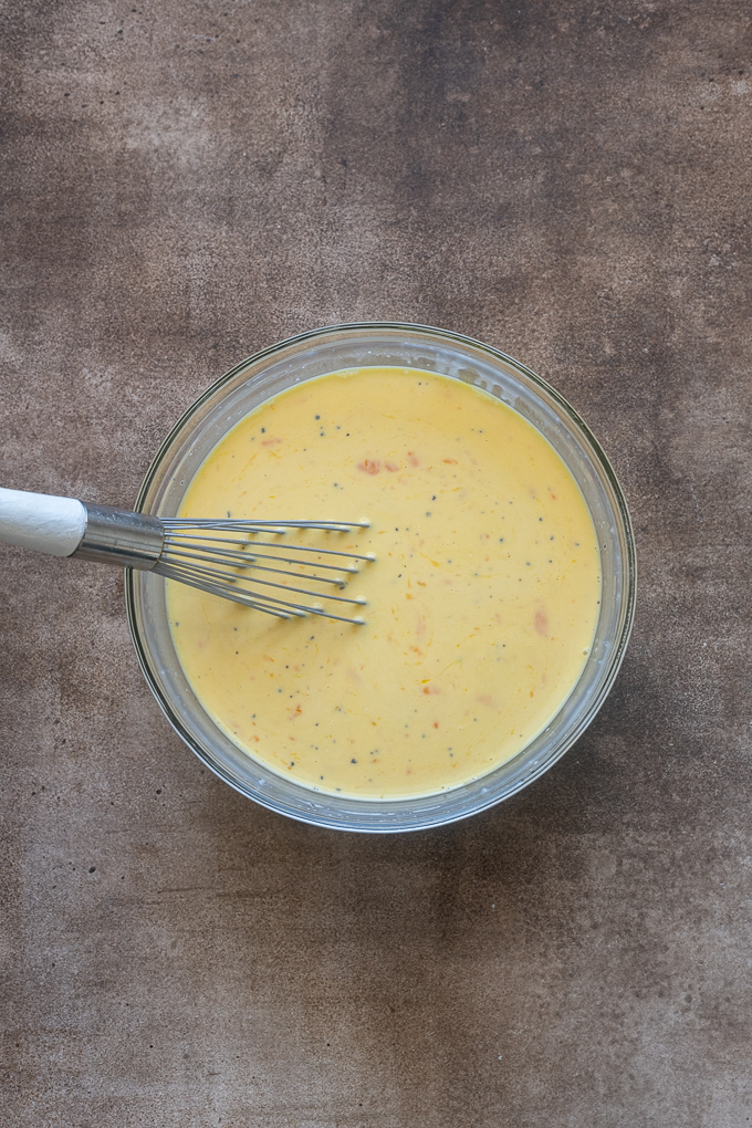 Eggs whisked with milk and parmesan cheese for sausage breakfast casserole.